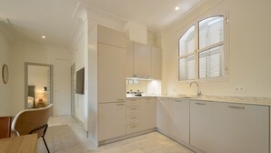 A modern kitchen with light-colored cabinets, a built-in oven, and a window with shutters. - Adriano 2.2 by Home at Homes (Sevilla)