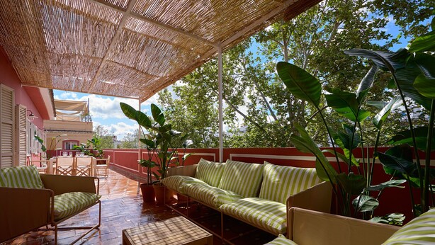 A covered patio with striped sofas, a wooden table, and potted plants. - Adriano 2.2 by Home at Homes (Sevilla)