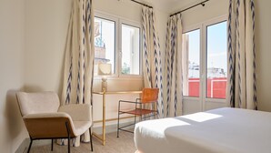 A hotel room with a bed, two chairs, a desk, and a window with curtains. - Adriano 2.2 by Home at Homes (Sevilla)