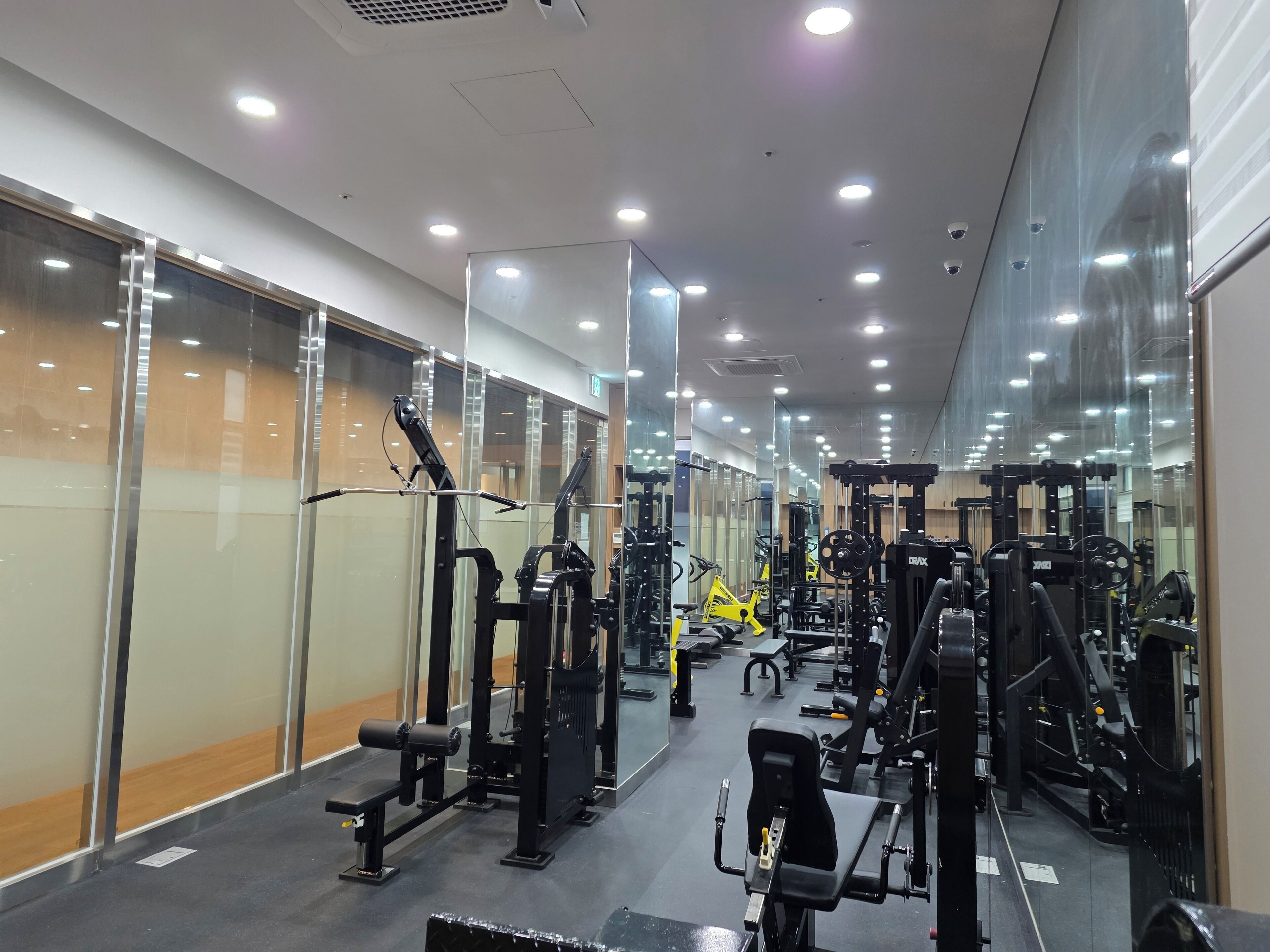 A gym with various exercise machines, mirrored walls, and a clean, modern design.