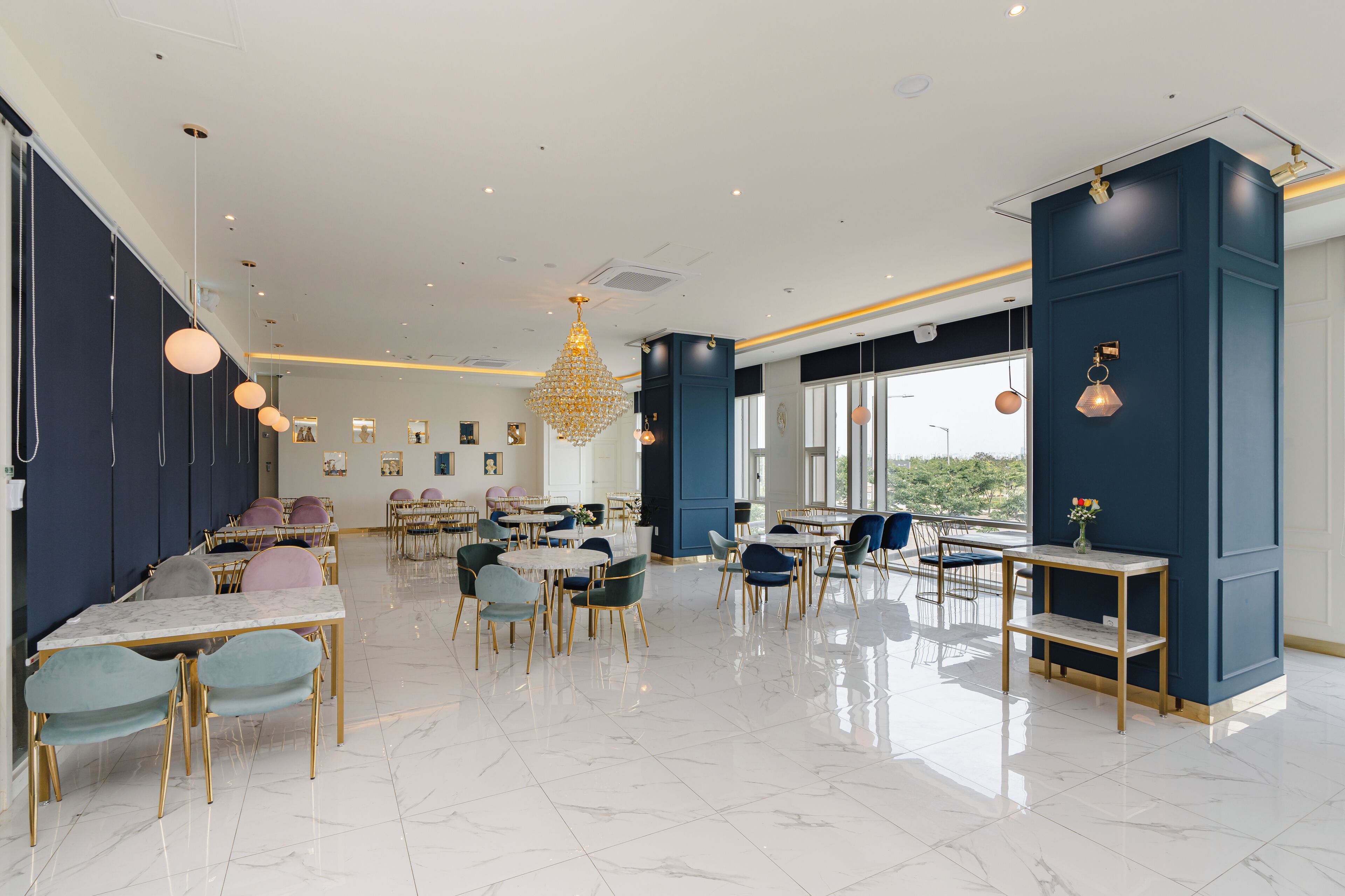 A modern dining area with marble flooring, blue and gold decor, and a large chandelier.