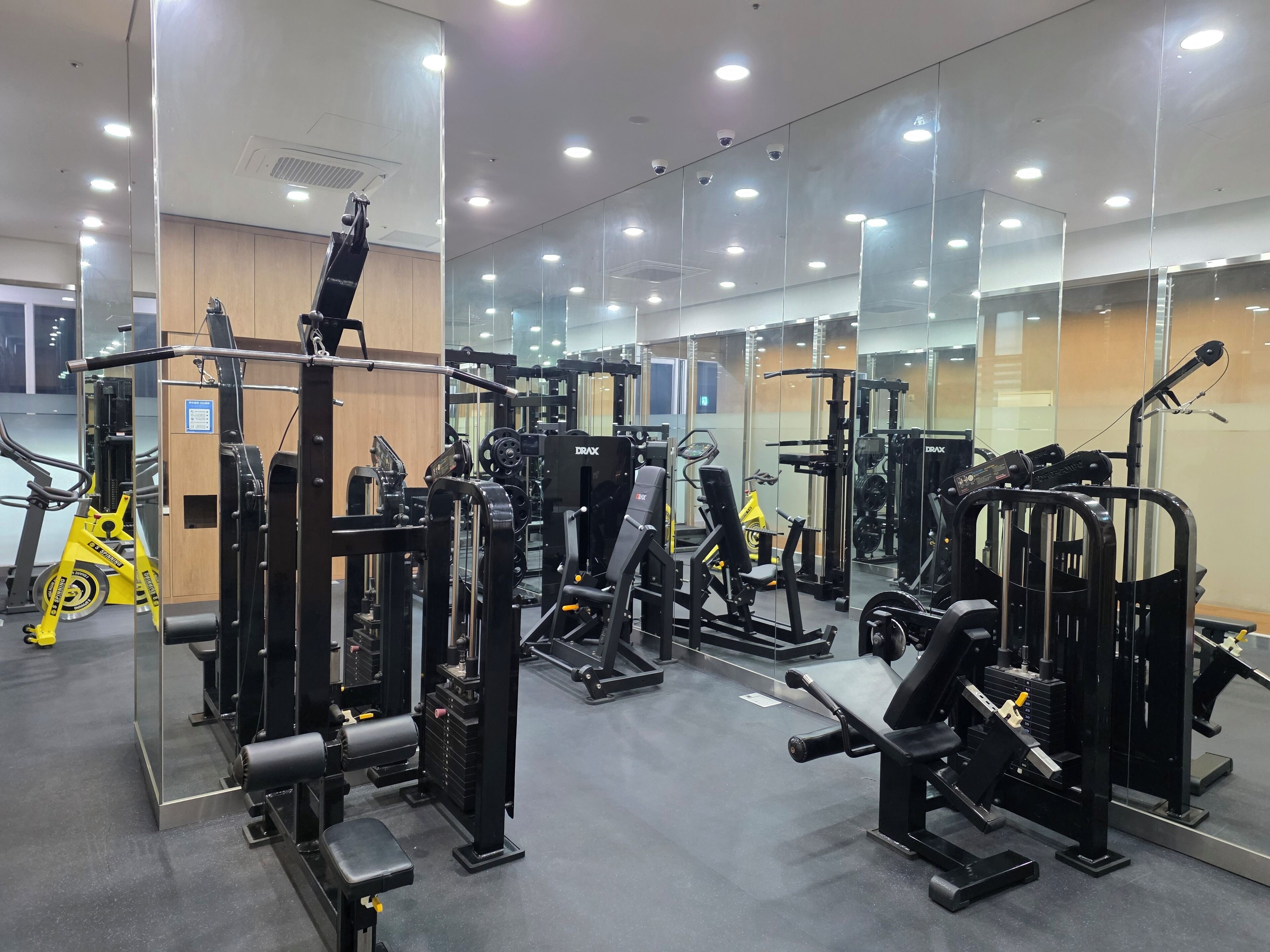 A gym with various exercise machines, mirrors on the walls, and a yellow exercise bike.