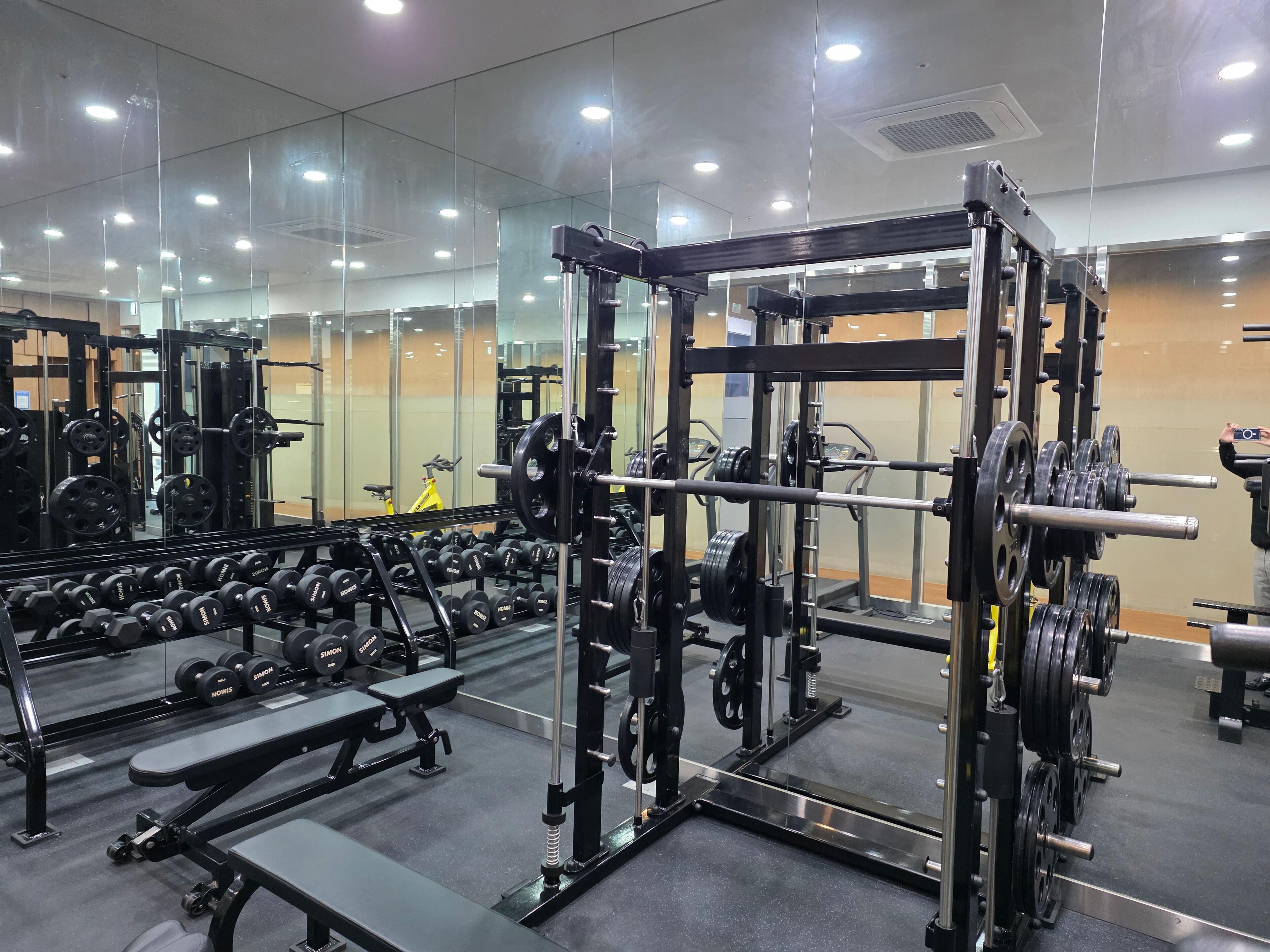 A gym with weightlifting equipment, benches, and dumbbells.