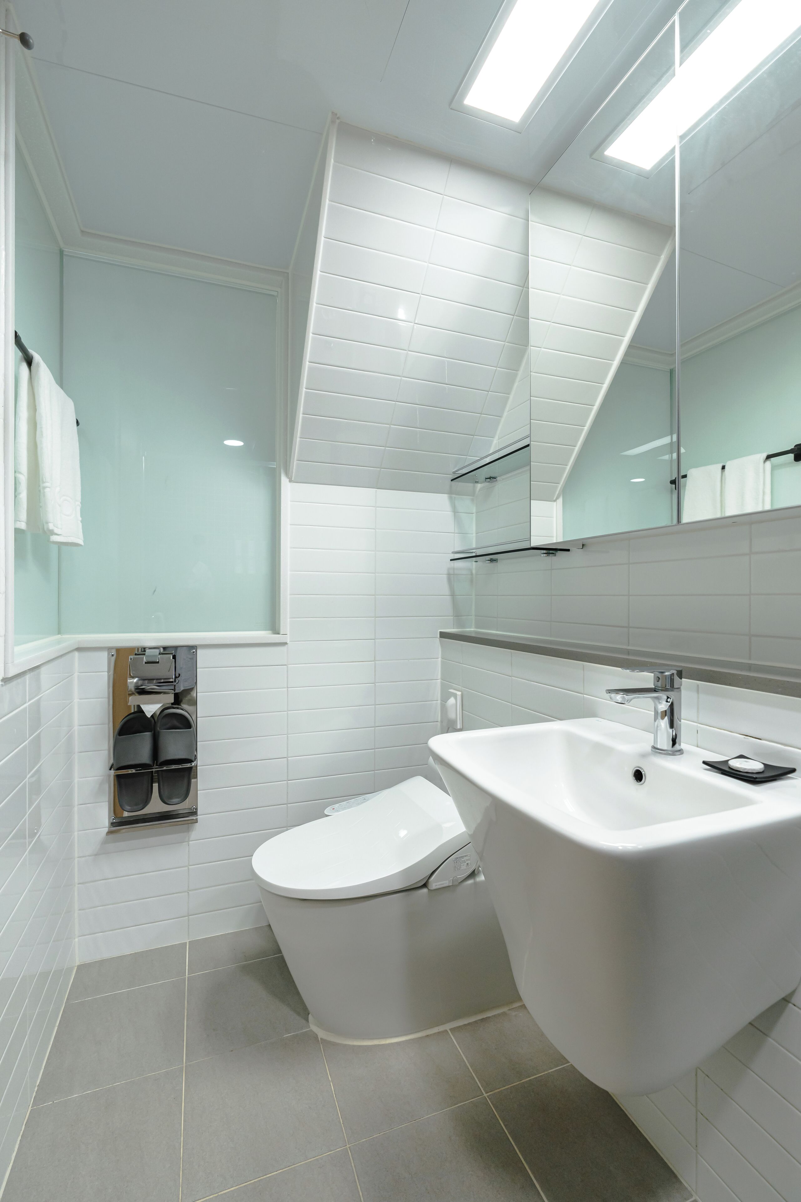 Ein modernes Badezimmer mit Toilette, Waschbecken mit Spiegel und Handtuchhalter.