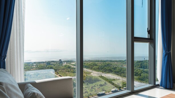 A room with a large window offering a view of a green landscape and a body of water. - SR Hotel Yeongjong (Incheon)