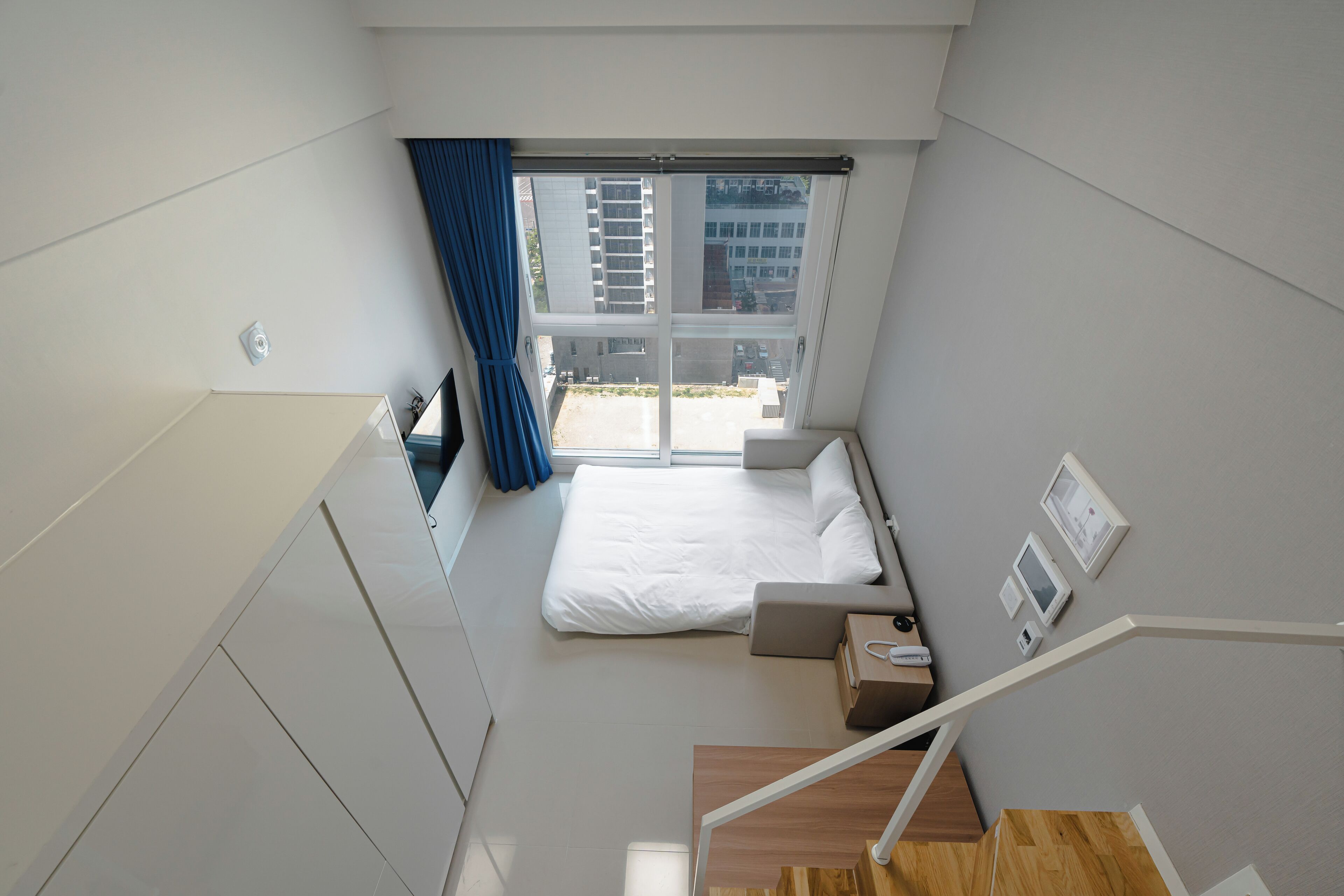 Habitación de hotel moderna con cama, un escritorio pequeño, una ventana con cortinas y vistas al exterior.