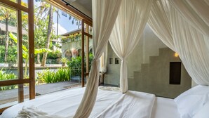 A bedroom with a large window, a bed with white linens, and a view of a garden. - Ubud Terrace by Betterplace (Ubud)