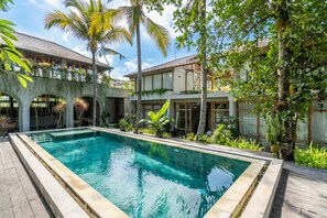 A rectangular swimming pool with a stone edge, surrounded by a wooden deck. - Ubud Terrace by Betterplace (Ubud)