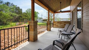 A covered patio area with stone pillars, a black metal fence, and outdoor furniture. - Edge of Main 5- Vineyard Views! (Fredericksburg)