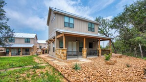 A two-story house with a covered porch, stone pillars, and a landscaped garden with rocks and greenery. - Edge of Main 5- Vineyard Views! (Fredericksburg)