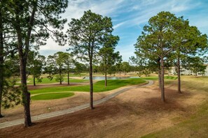 A golf course with trees, a pond, and a building in the background.