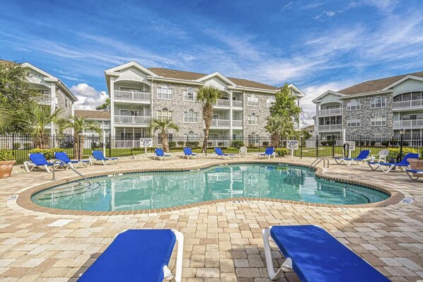 A pool area with lounge chairs and a stone building in the background.
