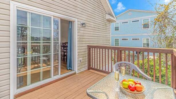 A deck with a glass table, fruit basket, and two glasses of champagne. - 2185 Sanibel Court (Myrtle Beach)