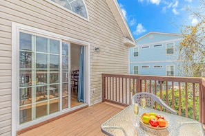 A deck with a glass table, fruit basket, and two glasses of champagne.
