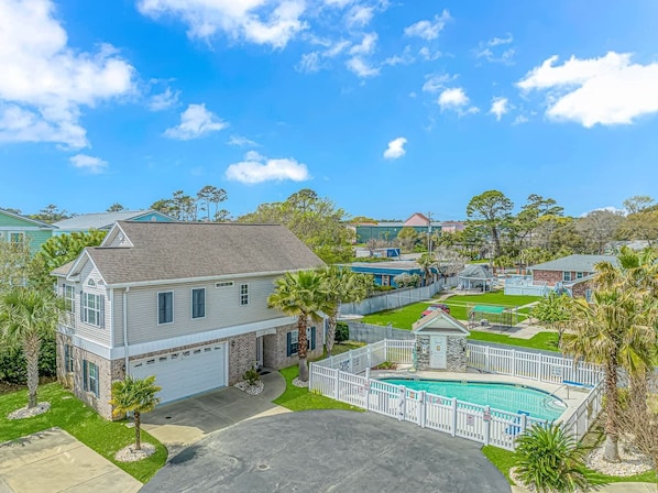 A residential property with a swimming pool, a fenced yard, and a garage.