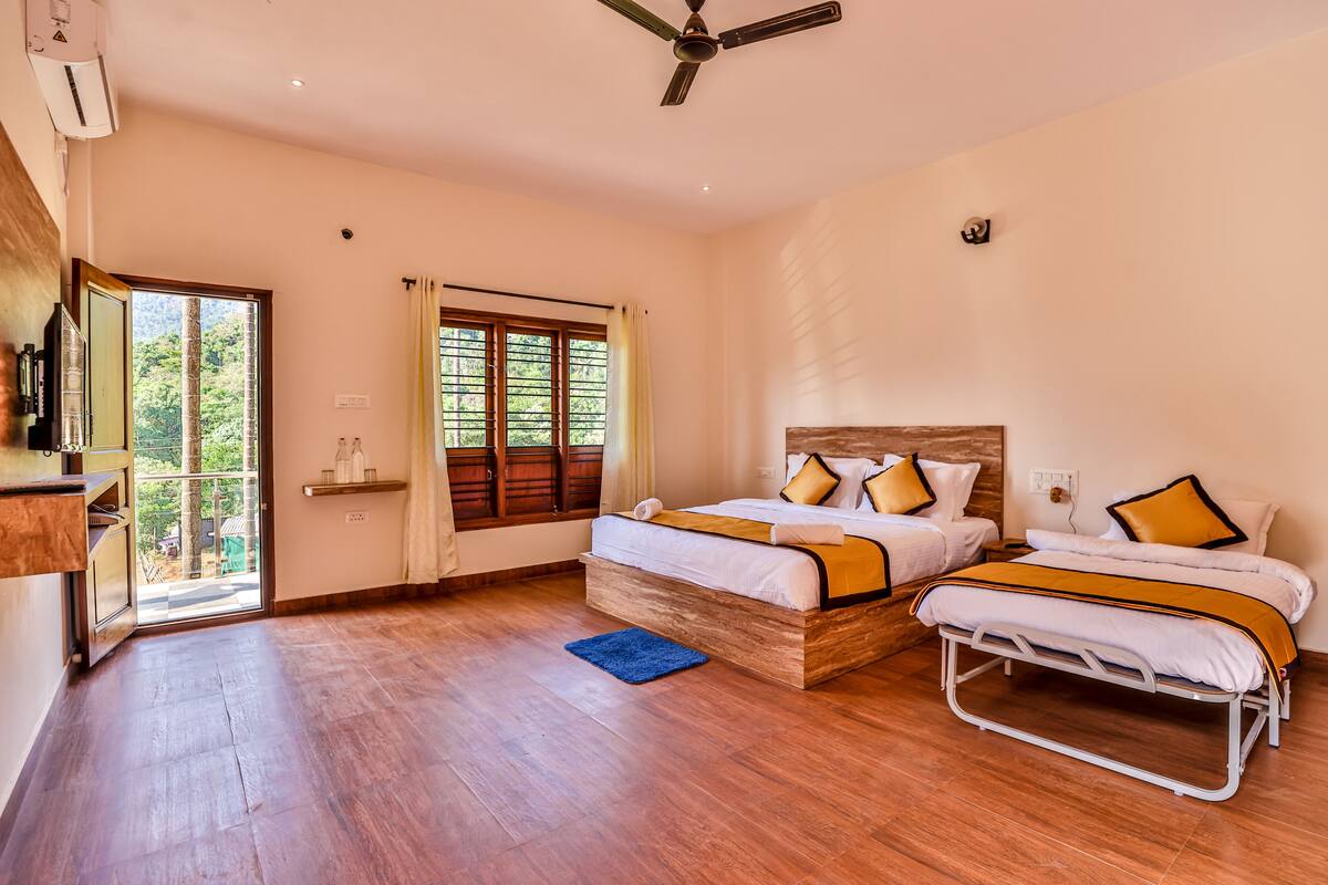 A bedroom with two beds, a ceiling fan, a window with curtains, and a wooden floor.