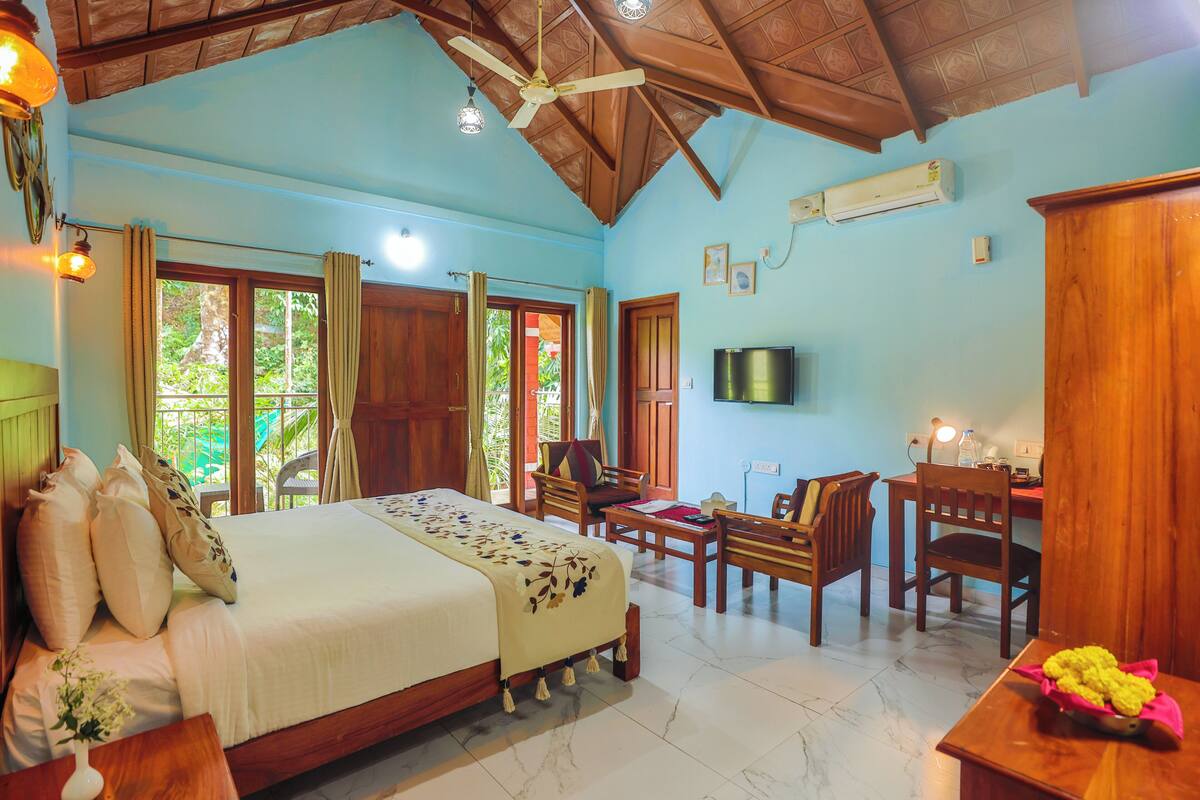 A spacious bedroom with a large bed, a desk, and a television.