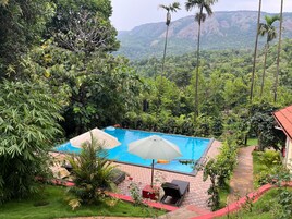 Una piscina con vistas a un paisaje verde y exuberante y montañas al fondo.
