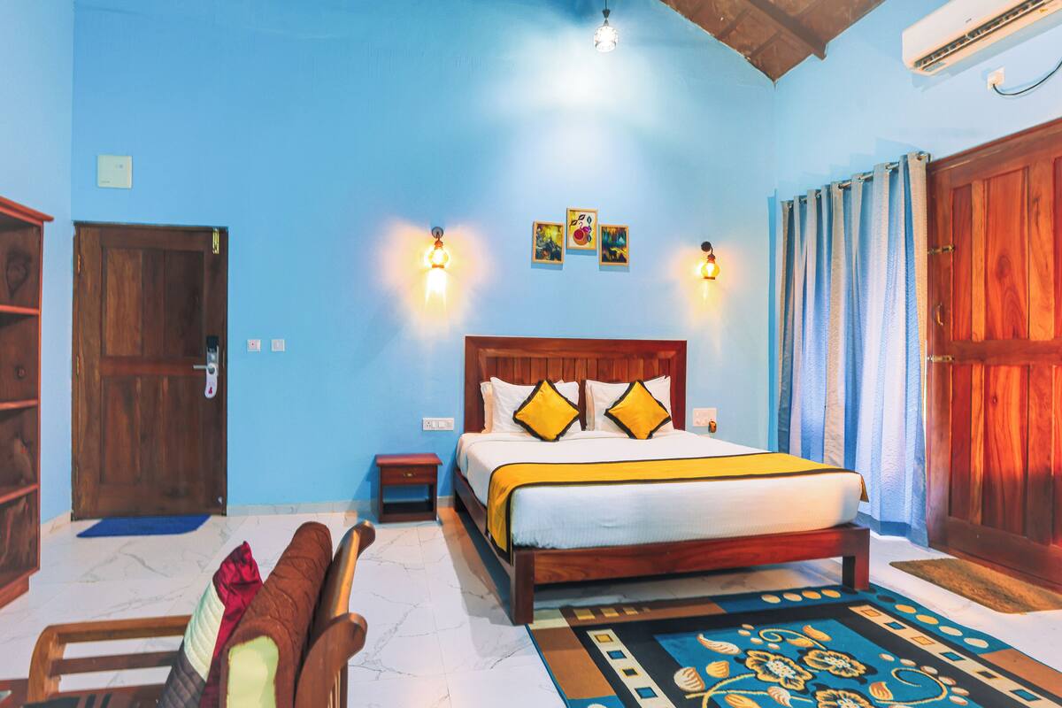A bedroom with a wooden bed, a nightstand, a blue wall, and a wooden door.