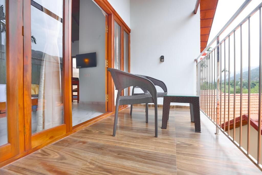 Ein Balkon mit Holzboden, einem Korbstuhl und einem kleinen Tisch.