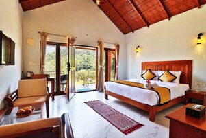 Un dormitorio amplio con una cama grande, cabecera de madera y vistas al exterior a través de una puerta corrediza de vidrio.