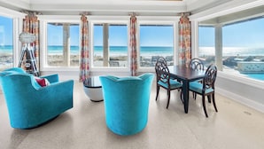A dining area with a view of the beach, featuring a wooden ceiling, large windows, and blue upholstered chairs. - "Beach Castle" | Private Beachfront home with heated pool, ping pong & pool table! (Santa Rosa Beach)