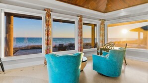 A room with large windows overlooking the ocean, featuring two turquoise chairs and a small table. - "Beach Castle" | Private Beachfront home with heated pool, ping pong & pool table! (Santa Rosa Beach)