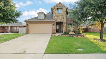 A two-story house with a stone facade, a garage, and a well-maintained lawn.