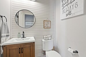 Ein Badezimmer mit weißem Waschbecken, Holzschrank, Toilette und Spiegel.