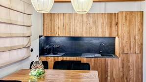 A compact kitchen with wooden cabinets, a black countertop, and a dining area with a glass-top table.