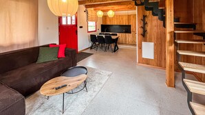 A modern living room with a brown sofa, a wooden coffee table, and a red door.
