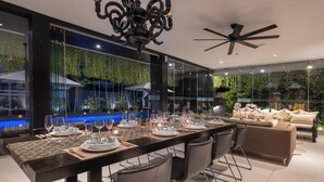 A modern dining area with a long table set for a meal, surrounded by comfortable seating.
