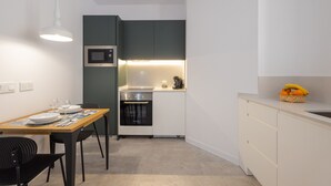 A compact kitchen with a microwave, oven, and a small dining area with a table and chairs. - The Sorolla Apartment V | AC & WiFi | 4 Guests (Valencia)