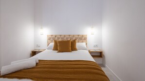 Une chambre d’hôtel moderne avec un grand lit, deux tables de chevet et une tête de lit ornée d’un motif géométrique.