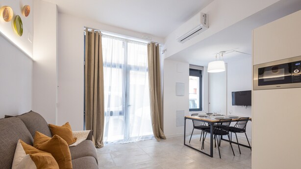 Un salon moderne avec un canapé, une table à manger et des chaises.
