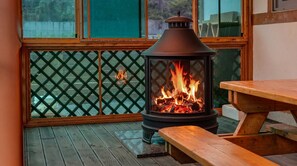 A wood-burning stove with a fire, a wooden table, and a lattice window. - Gyeongju Gampo Byeolbit Hanok Pension (Gyeongju)