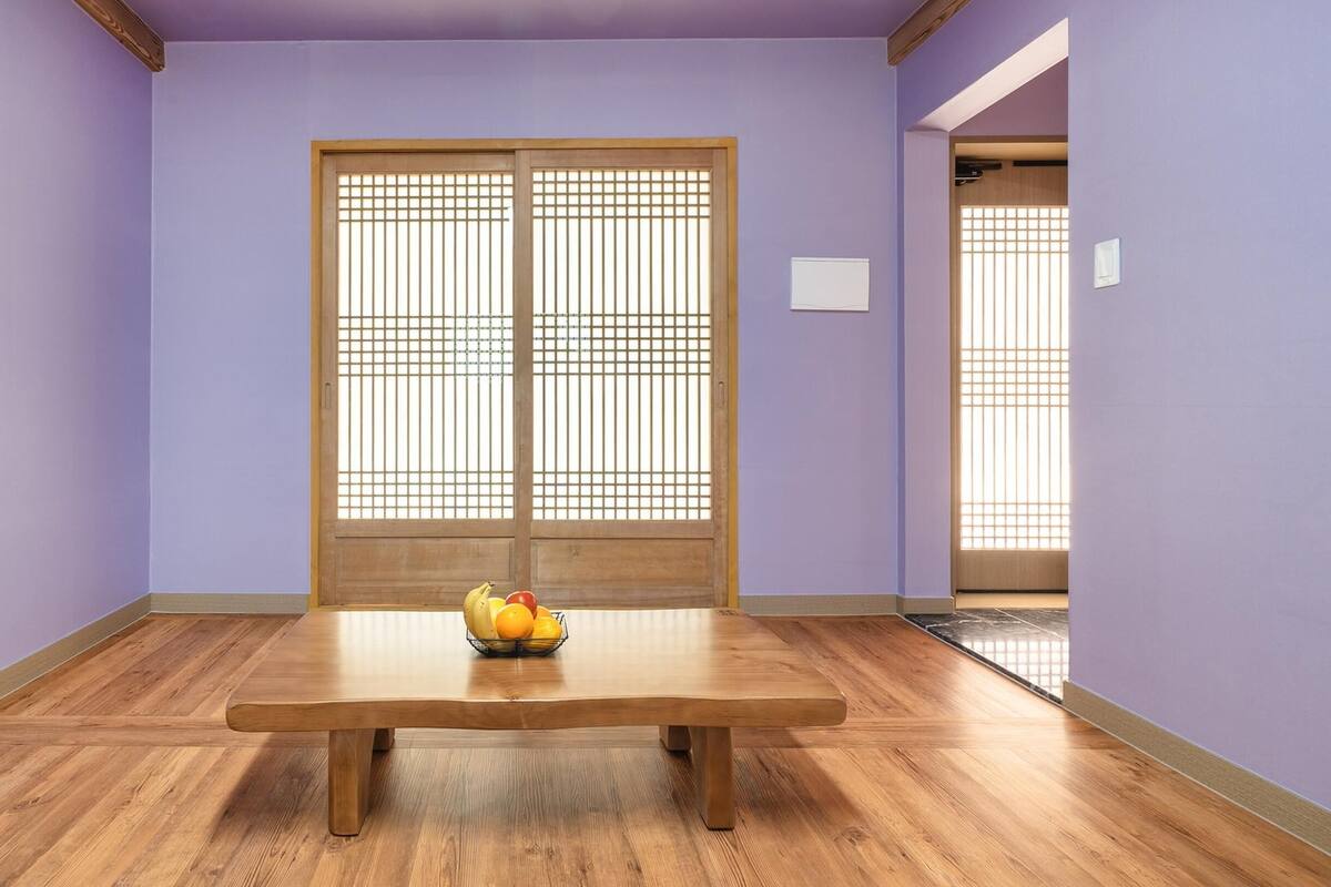 A room with a wooden table, a fruit bowl, and traditional sliding doors.