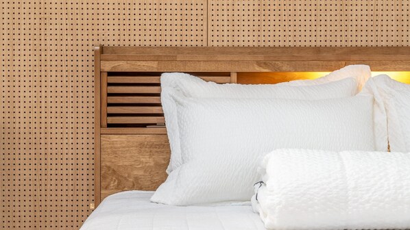 A neatly made bed with white bedding and pillows, a wooden headboard, and a perforated wall behind it. - Gyeongju Gampo Byeolbit Hanok Pension (Gyeongju)