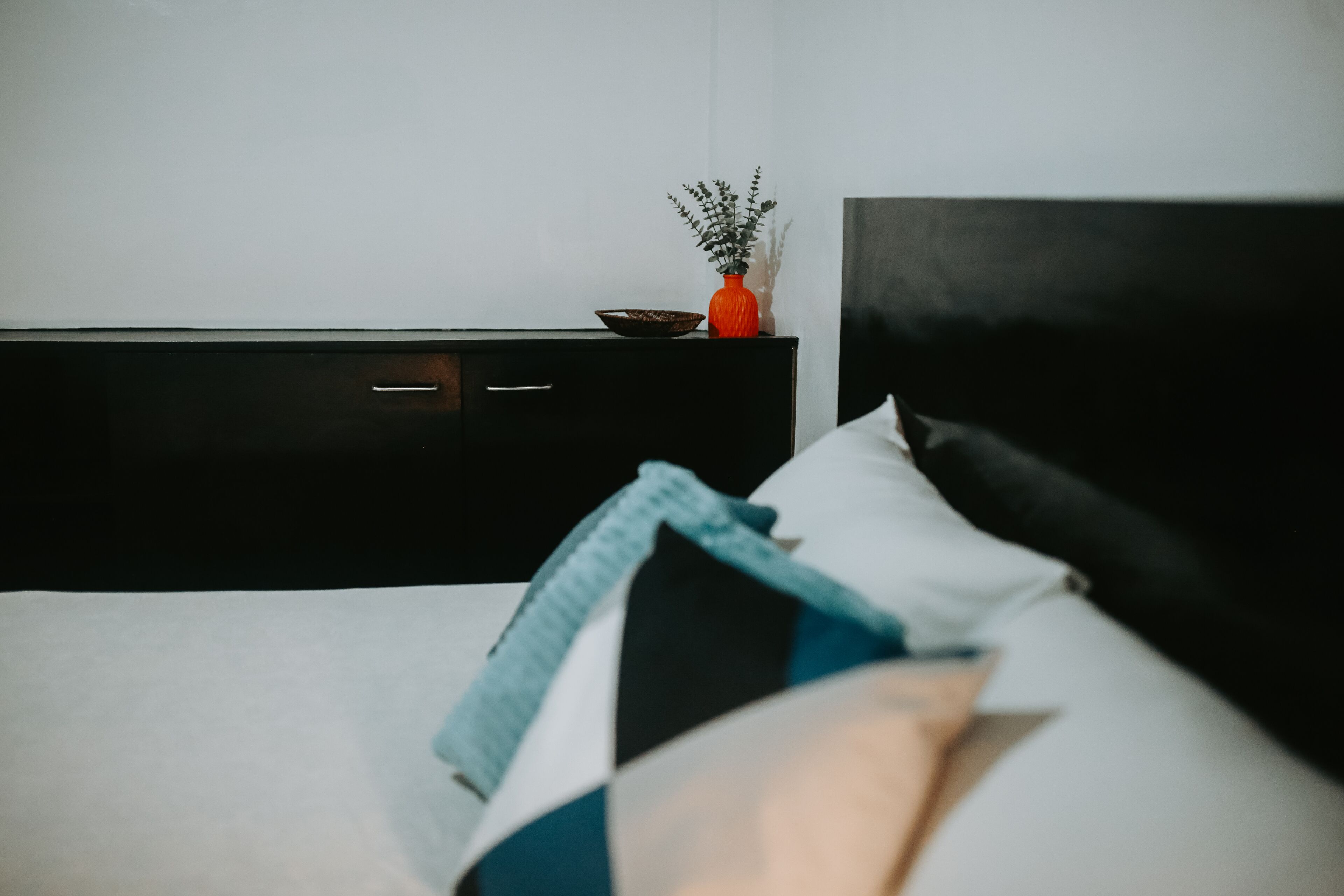 Una cama con cabecera negra, colchón blanco y varias almohadas.