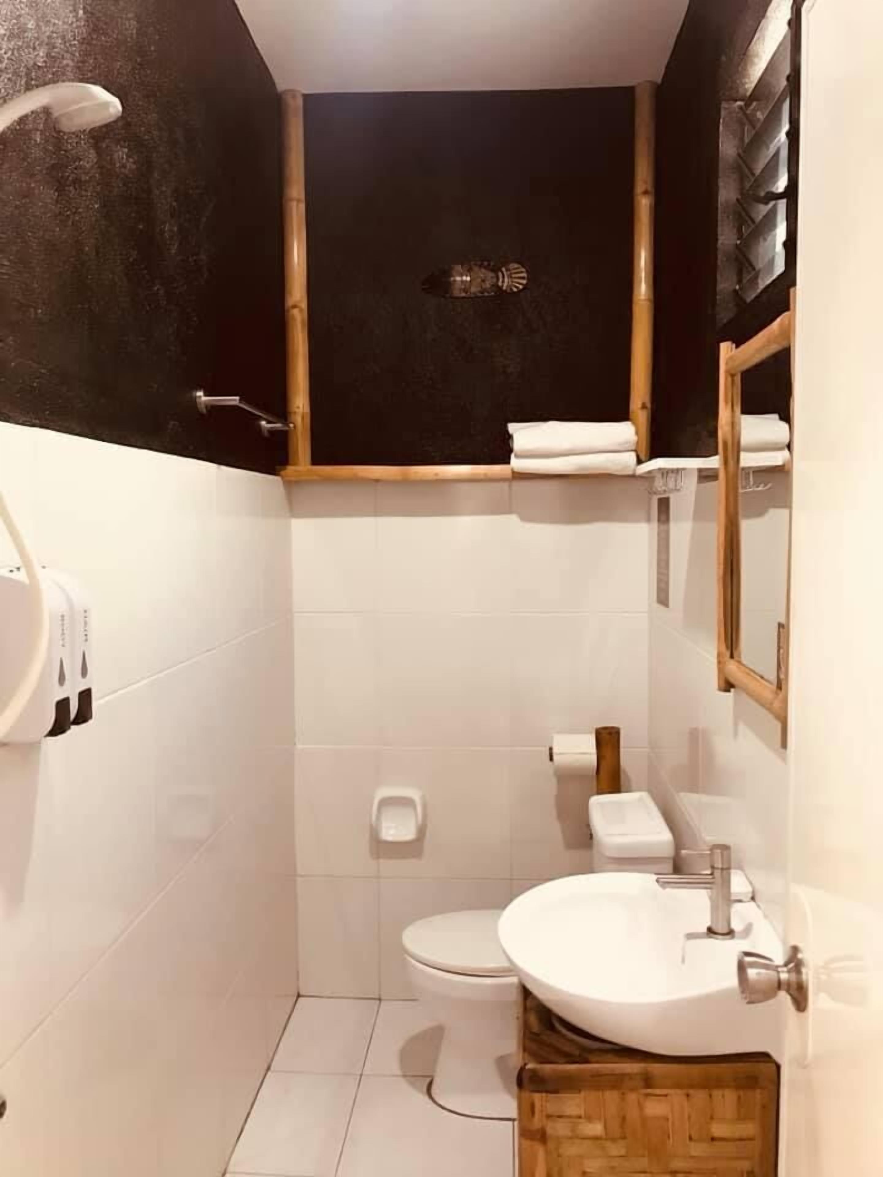 A small bathroom with a toilet, sink, and shower.