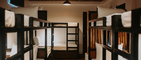 A bunk bed room with a wooden ceiling and a single hanging light fixture.
