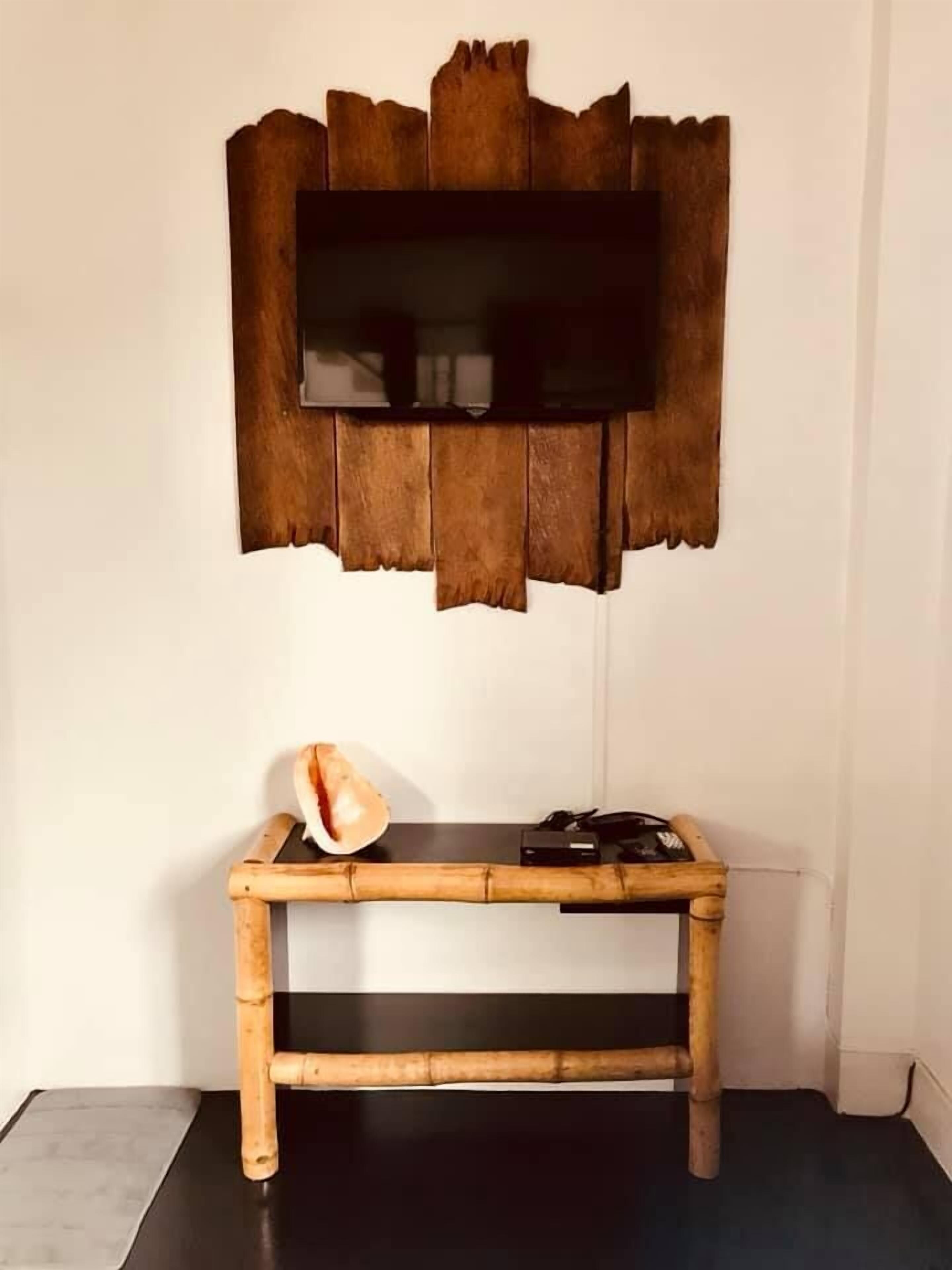 Una habitación con una consola de madera, un televisor sujeto a un marco de madera y un estante pequeño.