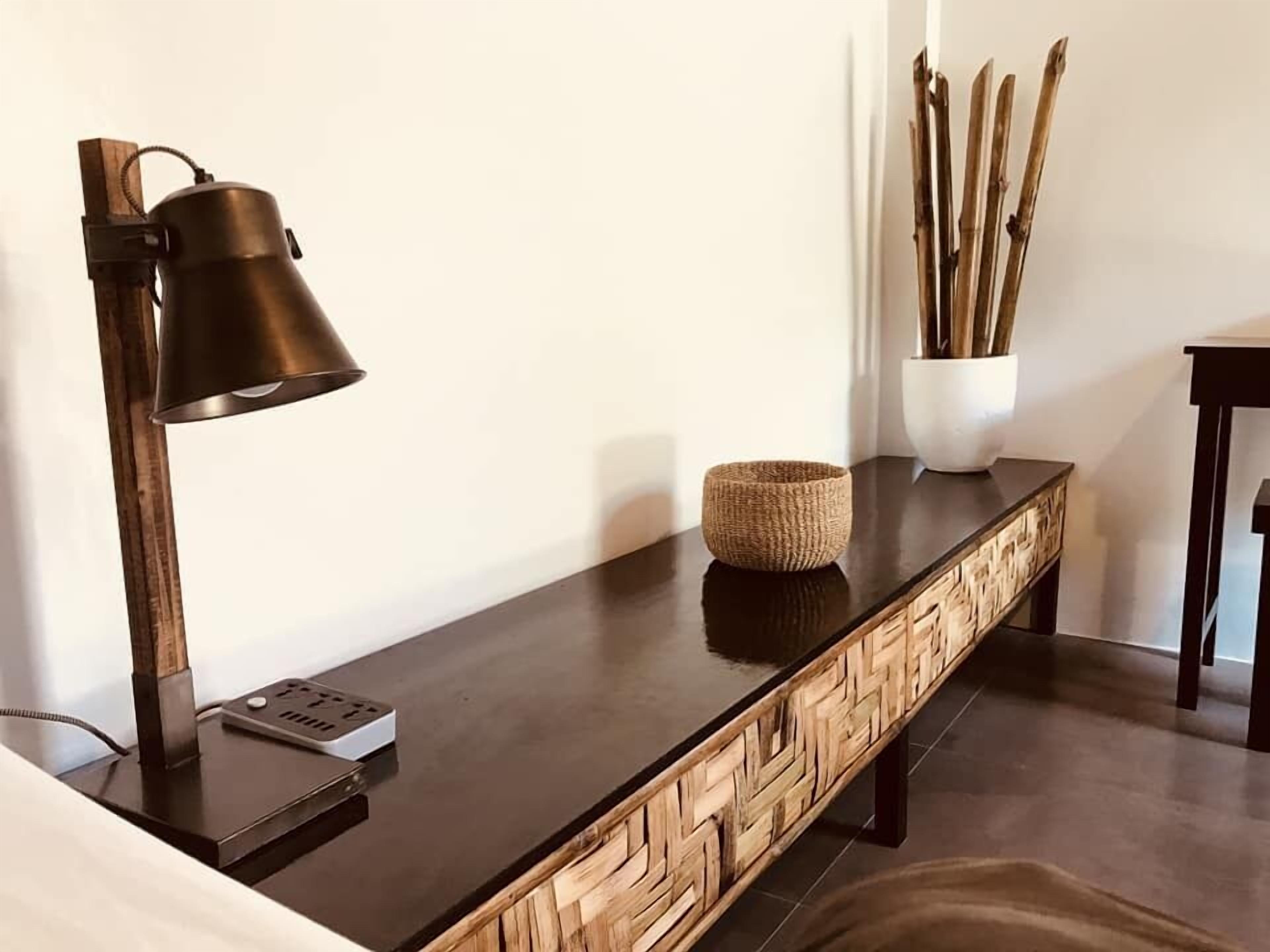 A modern, minimalist desk with a sleek black surface, a wooden side panel, and a black desk lamp.