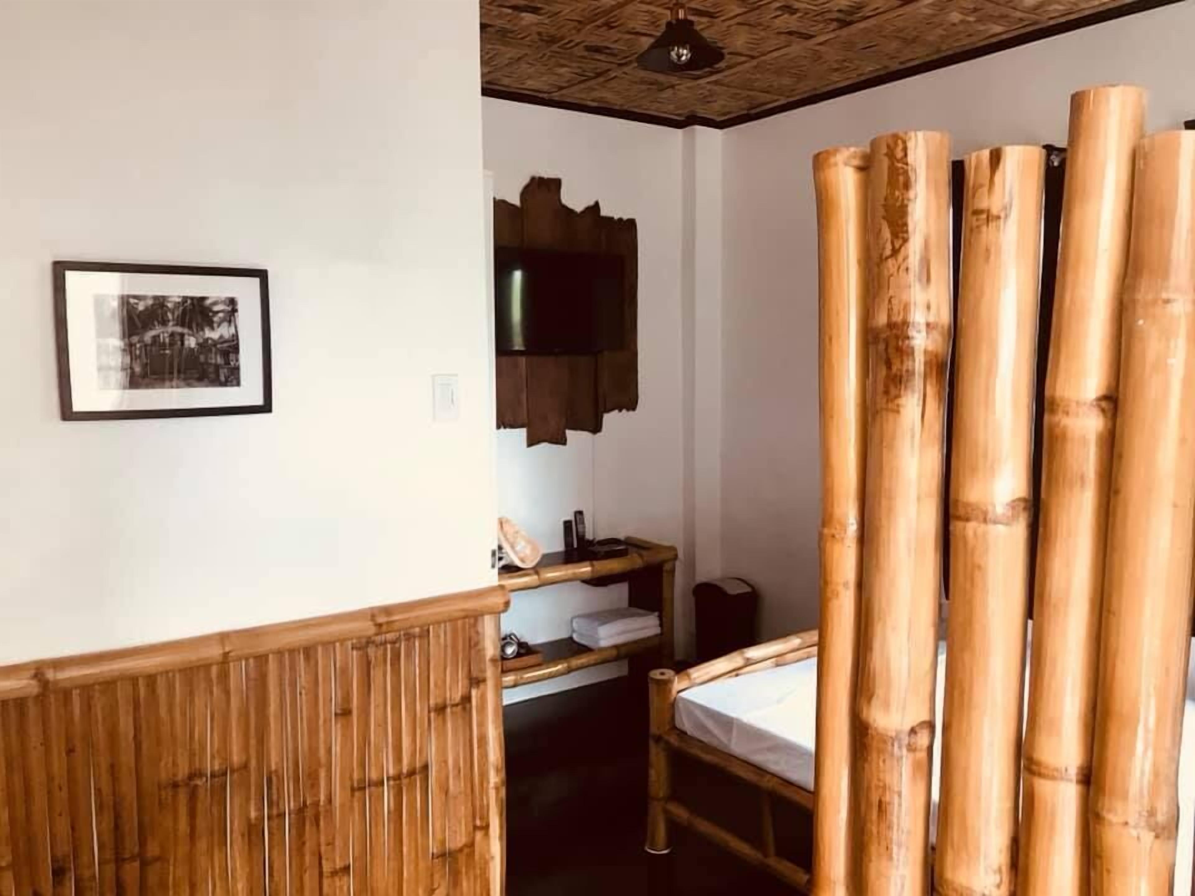 Una habitación con una cama, un armario de madera, un cuadro enmarco y una estructura grande de bambú.