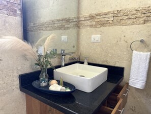 Bathroom features a large mirror, a sink with soap and lotion, and a towel rack with a towel.