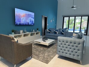Relax in style with a large flat-screen TV, comfortable sofa, and armchair, surrounded by a beautiful pool view.