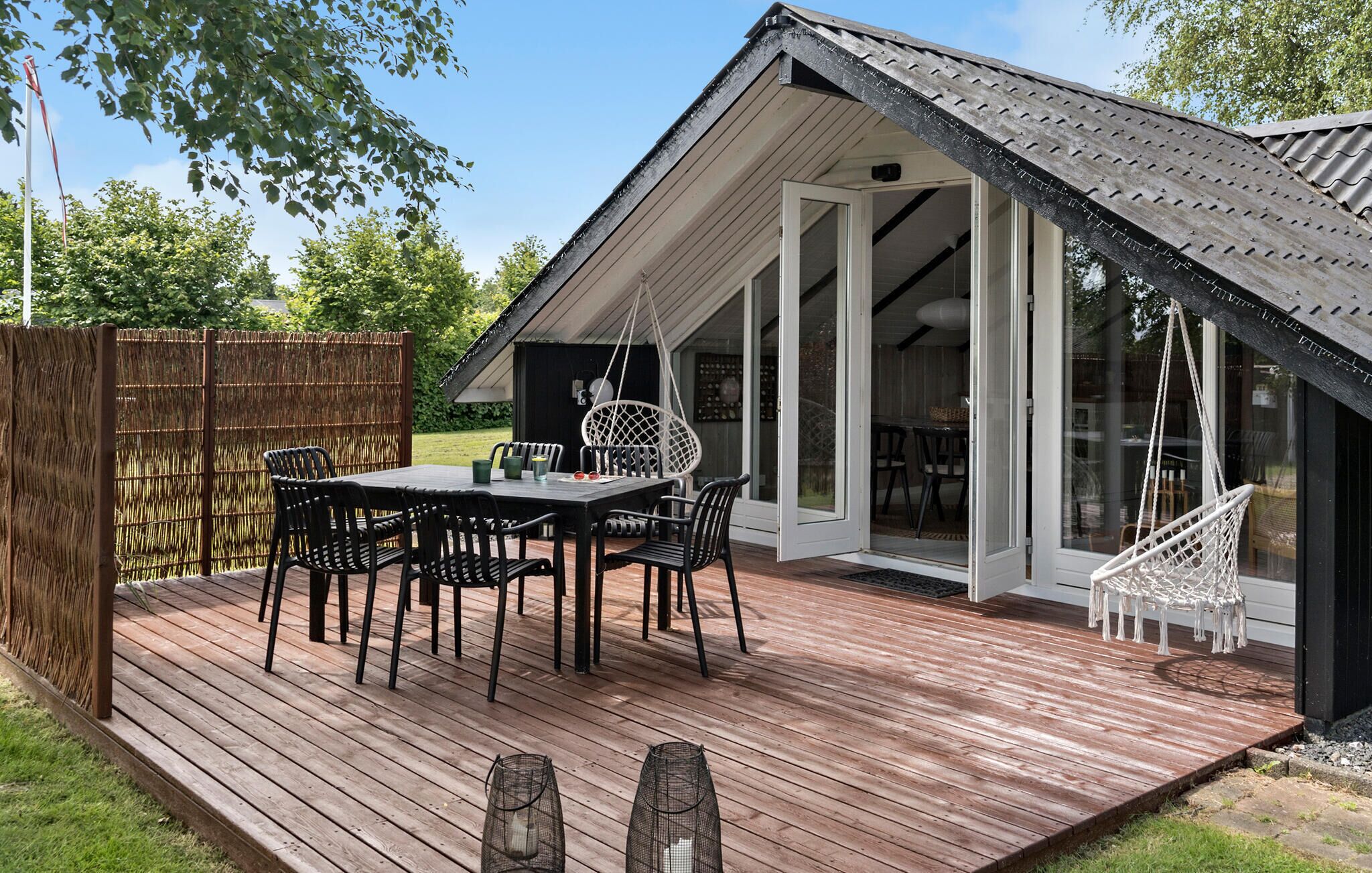 Une terrasse extérieure avec une table et des chaises pour les repas, un fauteuil suspendu et une balançoire.