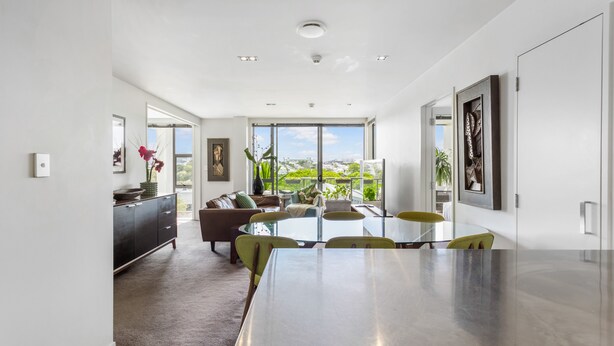 A modern living room with a dining area, large windows, and a view of greenery. - Kingsland, Auckland 2BR 2Bath 2CarPark Apt (Auckland)