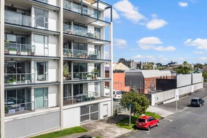Un immeuble résidentiel à plusieurs étages, doté de balcons, d’un espace de stationnement et surplombant un ciel dégagé.