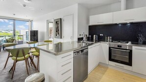 A modern kitchen with white cabinetry, a stainless steel dishwasher, and a black tiled backsplash. - Kingsland, Auckland 2BR 2Bath 2CarPark Apt (Auckland)